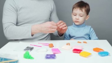 Baba ve oğlunun gri arka planda plastik oyuncaklardan oyuncaklar yonttuğu çekimler