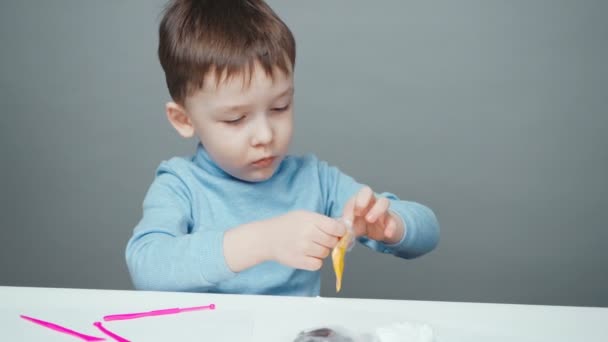 Niño de cuatro años esculpiendo en plastilina sobre fondo gris — Vídeos de Stock