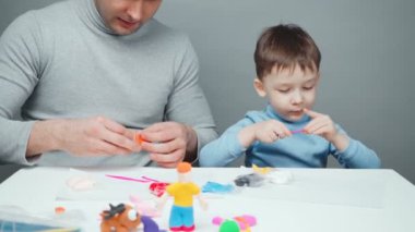 Baba ve oğul plastikten hayvan yontuyorlar.