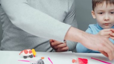 Baba ve küçük çocuk plastikten hayvan yapıyorlar.