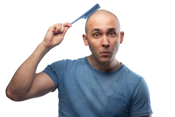 Foto de homem careca confuso em camiseta azul com escova de cabelo — Fotografia de Stock