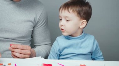 Baba ve küçük çocuk plastikten hayvan yapıyorlar.