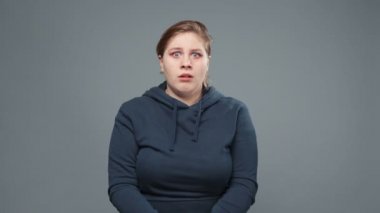 Sweatshirt giymiş korkmuş şişman bir kadının videosu.