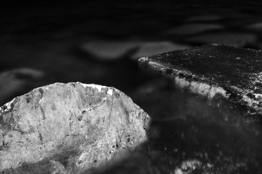 Siyah ve beyaz, tek renkli, soyut, arka plan, iki taşın görülebilir dokusu olan suya batırılmış hali. Karanlık ve kayalık arazideki sakinlik atmosferi. Kayalık detay, yakın plan..