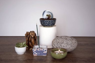 Home altar. Spiritual decor arrangement with burning candle, incense sticks, stone and fresh plants. Spirituality at home concept. Mini Zen Japanese style home decoration.