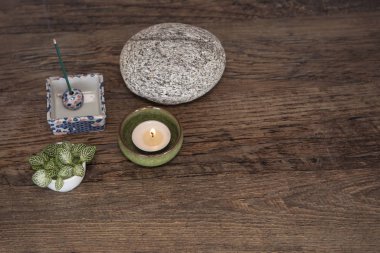 Spiritual deco arrangement with burning candle, incense sticks, round stone and fresh leaves from above. Mindfulness, meditation concept. Zen style background with copy space.