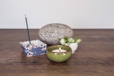 Home altar. Burning candle in a ceramic casing, incense sticks, stone and fresh plants. Spirituality at home concept. Daily meditation routine. Mini Zen Japanese style home altar. Relaxation technics.