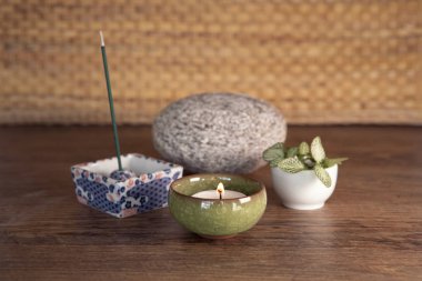 Smoking and smelling joss stick, candle with flame. Wooden background. Wellbiing, yoga, meditation equipment.