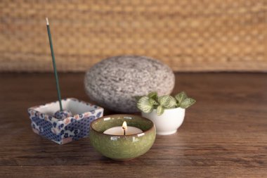 Smoking and smelling joss, candle light, stone, fresh leaves on wooden background. Wellbiing, yoga, meditation equipment.