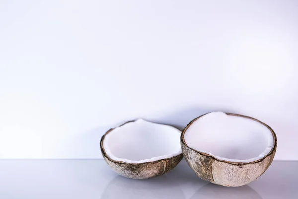 ココナッツの2つの半分の滑らかな明るい背景に横たわっている トロピカルフルーツニュートラルでエレガントな背景 健康的な新鮮なココア — ストック写真