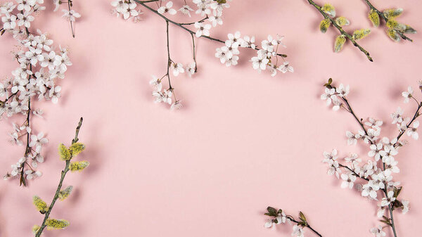 Flowering branches, white twig flowers and pussy willow catkins on pink background. Spring, easter season border background, banner. Springtime floral, flat lay arrangement.