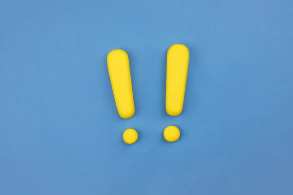 Two yellow vivid exclamation marks on blue background. Flat lay, warning sign, keep attention, alert concept.