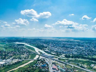 Şehir merkezinden ve yerleşim yerinden geçen nehir ve köprünün insansız hava aracı görüntüsü.