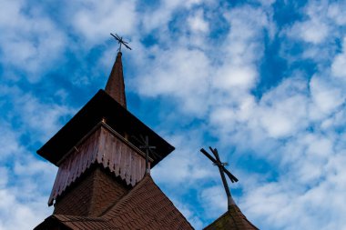 Maramures 'da bulutlu bir gökyüzünde eski ahşap bir kilisenin çan kulesinin yukarıdaki görüntüsü.