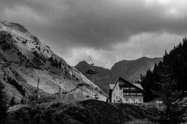 Dağ dağ dağ evinin siyah beyaz kompozisyonu ve arka planında dağlar var.
