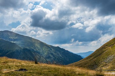 Sönük ateş, arka planda dağlar ve yukarıda kabarık bulutlar
