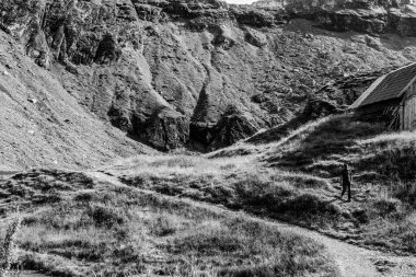 Dağ dağ evinin yakınındaki dağ yolunda yürüyen bir adamın siyah ve beyaz kompozisyonu.
