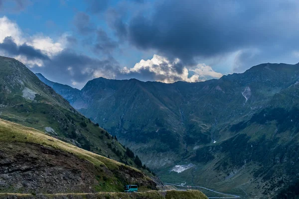 Ônibus Passando Estrada Montanha Com Montanhas Fundo Nuvens Escuras Acima — Fotografia de Stock