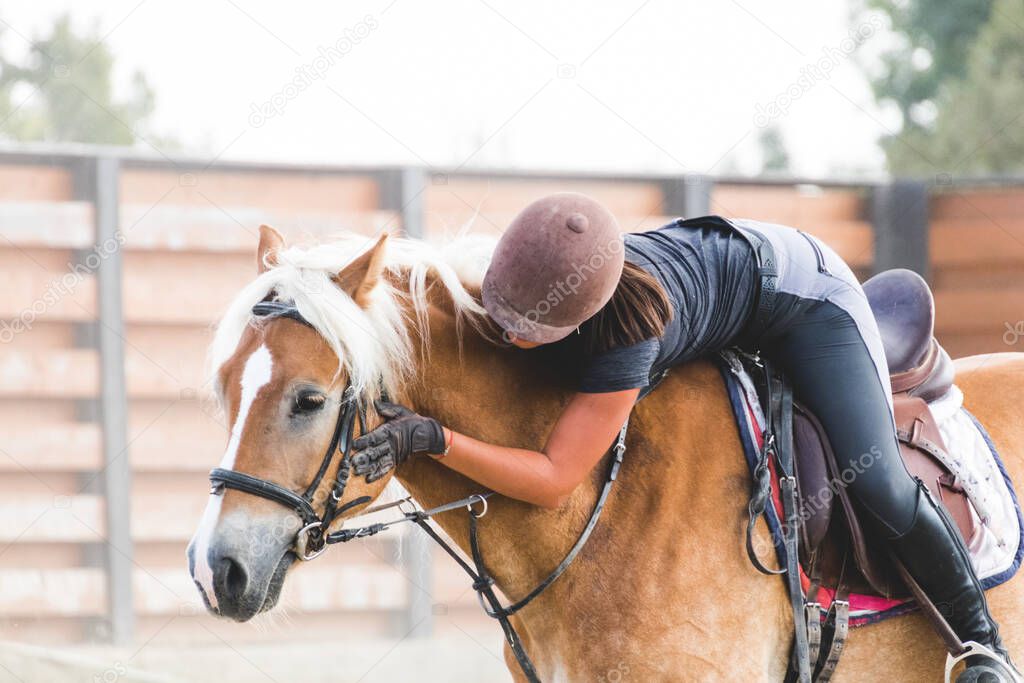 Woman jockey gently caressing a horse on its head