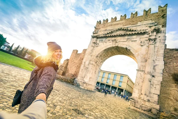 Man following beloved woman on autumn vacation - Fun concept with travelers in Rimini old town at Augustus Arch - Boyfriend and girlfriend around the world - Vivid contrast filter with enhanced sunset — ストック写真