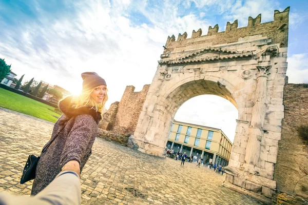 Hombre siguiendo a la querida mujer en las vacaciones de otoño - Concepto divertido con los viajeros en el casco antiguo de Rimini en Augustus Arch - Novio y novia de todo el mundo - Filtro de contraste vívido con puesta de sol mejorada —  Fotos de Stock