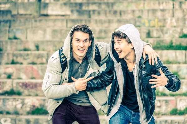 Young hipster brothers having fun with each other - Best friends sharing free time together in urban area outdoors - Handsome guys with winter fashion hoodie clothes enjoying everyday life moments