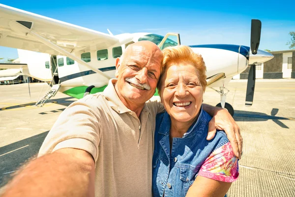 Senior happy couple taking selfie with private ultralight plane for tour around the world - Active elderly concept with retired people enjoying pension moments - Bright sunny afternoon color tones — Stock Photo, Image