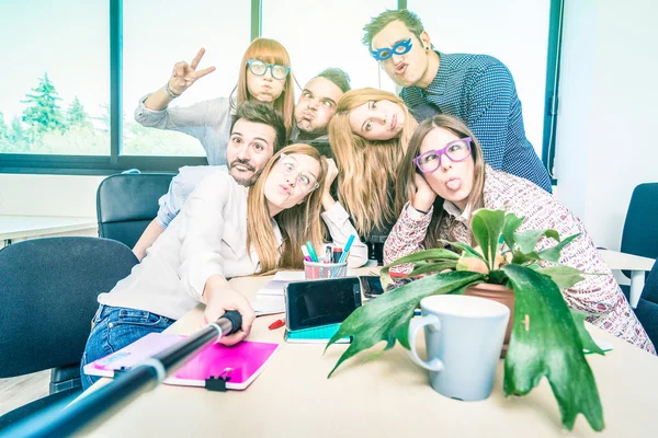 Grupo de estudiantes felices trabajadores empleados tomando selfie con palo - Concepto de negocio universitario de recursos humanos en el tiempo de diversión laboral - Empresarios de puesta en marcha en la oficina de la universidad - Lomo brillante filtro —  Fotos de Stock