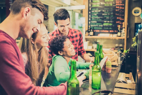 Amigos multirraciales bebiendo cerveza y divirtiéndose en el restaurante bar de cócteles - Concepto de amistad con la gente disfrutando del tiempo juntos - Filtro lomo vintage con viñetas y enfoque en la chica riendo —  Fotos de Stock