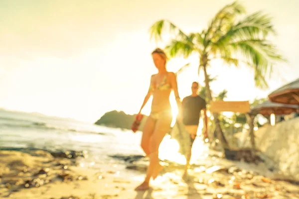 Blurred defocused silhouette of travelers people before sunset - Travel and wanderlust concept with couple at Las Cabanas beach by El Nido Palawan - Warm bright filter - Tilted horizon composition — Stock Photo, Image