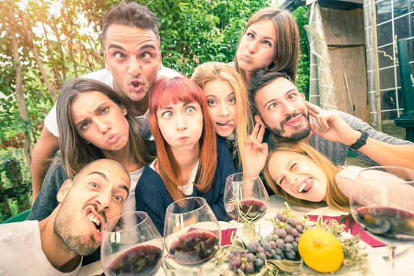 Beste Freunde beim Selfie im Freien mit Hintergrundbeleuchtung - fröhliches Jugendkonzept mit jungen Leuten, die gemeinsam Wein trinken - Heiterkeit und Freundschaft bei der Weinlese - weicher entsättigter Filter Stockbild