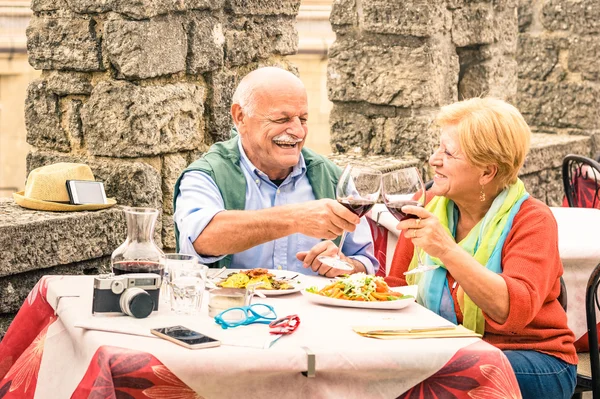 Senior couple having fun and eating at restaurant during travel - Mature man and woman wife in old city town bar during active elderly vacation - Happy retirement concept with retired people together — Stock Photo, Image