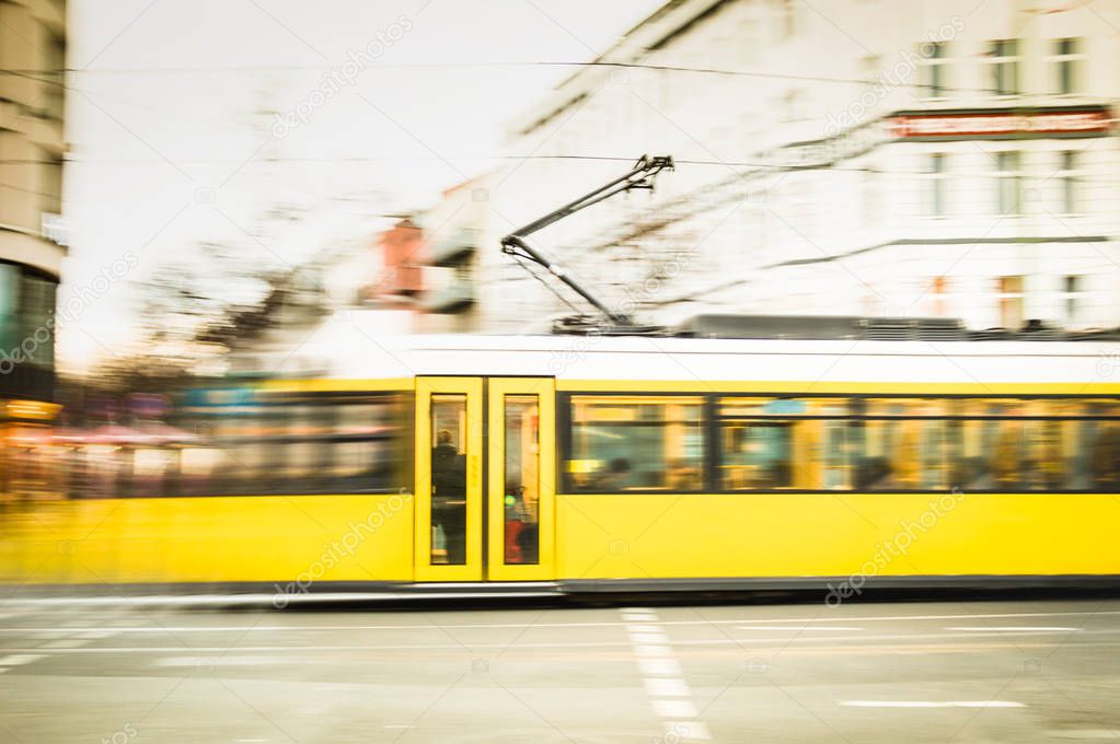 Blurred motion of defocused yellow tram on the streets of Berlin - Transport concept with public vehicle speeding at rush hour on city road - Warm vintage filter with blurry composition