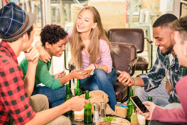 Багаторасові друзі групують пиво і розважаються з телефонами в ресторані коктейлів Концепція дружби з людьми, які насолоджуються часом разом - Невелика глибина різкості з акцентом на середню дівчину — стокове фото
