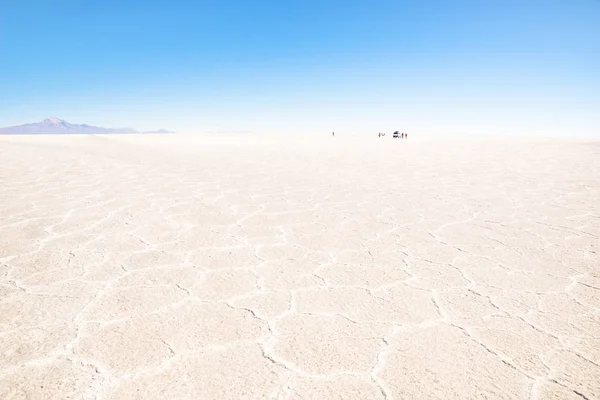 Unrecognizable people and off road vehicle on the horizon of Salar De Uyuni - World famous nature wonder destination in Bolivia - Travel and wanderlust concept in South American exclusive location — Stock Photo, Image