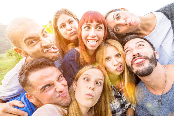 Best friends taking selfie outdoor with back lighting - Happy youth concept with young people having fun together - Cheer and friendship at picnic - Warm vivid filter with focus on redhead woman