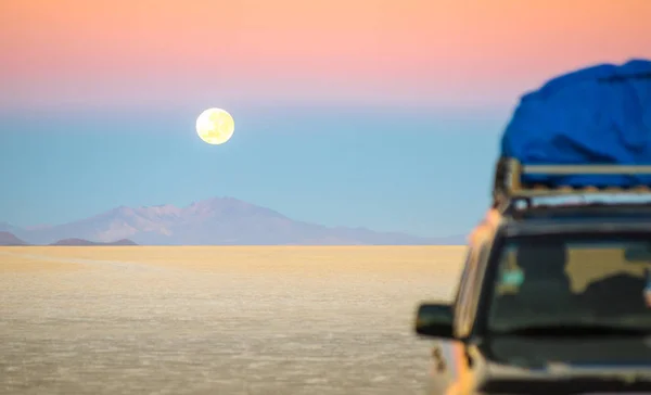 Puesta de sol de luna llena con vehículo todoterreno en Salar De Uyuni - Lugar de maravilla de la naturaleza mundialmente famoso en Bolivia - Concepto de viaje y ansia en destino exclusivo sudamericano - Enfoque en el infinito — Foto de Stock