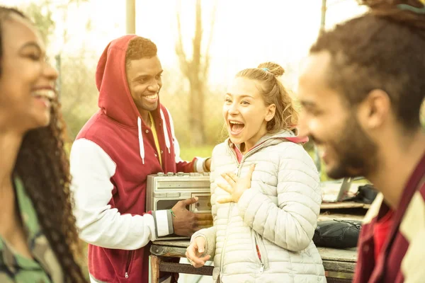Group of multiracial friend couples having fun time out at park in autumn winter time - Youth friendship concept with people together outdoors - Focus on blond young woman - Warm contrasted filter — Stock Photo, Image