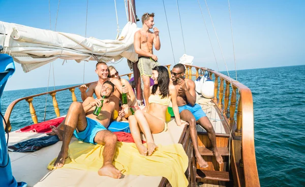 Felices amigos multirraciales bebiendo cerveza y divirtiéndose en la gira de fiesta en barco de vela - Concepto de amistad con jóvenes multirraciales brindando juntos en velero - Ubicación exclusiva de estilo de vida de viaje — Foto de Stock