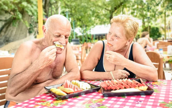高级的夫妻有乐趣吃时令水果在泰国餐馆酒吧户外-成熟的男人和女人在活跃的老年度假-快乐退休概念与人民在一起 — — 温暖影子筛选器 — 图库照片