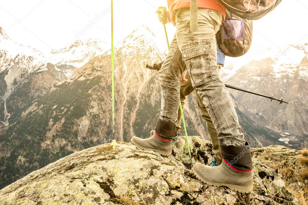 Close up of trekking legs and boots on french alps - Hiker with backpacks and sticks walking on mountain - Wanderlust travel concept with sporty people at excursion in wild nature - Focus on left shoe