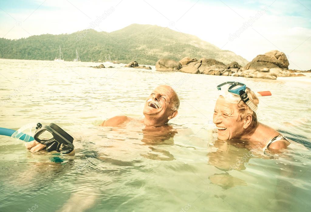 Senior couple vacationer having genuine fun on tropical Koh Lipe sea in Thailand - Snorkel tour in exotic scenario - Active elderly and travel concept around world - Warm desaturated greenery filter