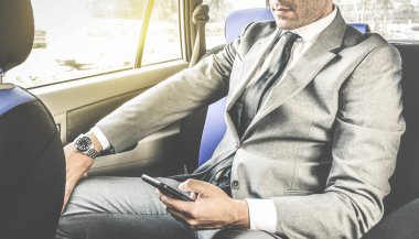 Taksi smartphone - iş kavramı ile akıllı telefon kullanan modern adam - yumuşak vintage penceresinden yapay güneş ışığı ile düzenleme ile sms manifatura süre oturan genç yakışıklı işadamı
