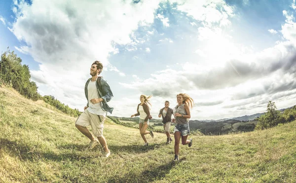 Группа друзей, свободно бегущих по травяному лугу - Концепция дружбы и свободы с молодыми счастливыми людьми, свободно передвигающимися во время кемпинга - Винтажный обесцвеченный фильтр с контрастным солнечным светом — стоковое фото