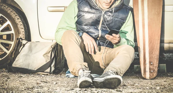 Homem jovem hipster ouvir música no celular telefone inteligente ao lado de seu carro com roupas de moda de viagem - Conceito de tecnologias modernas com cara no estilo de vida retro vintage - Filtro de contraste dessaturado — Fotografia de Stock
