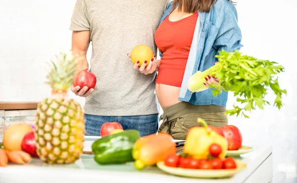 Hamile kadınla sağlıklı Vejetaryen yiyecekler ile mutfakta yemek Genç çift ve meyve - ev hazırlama vegan yemek biyo sebze ile insanlarla aşk kavramı - yandan orange ile odak — Stok fotoğraf