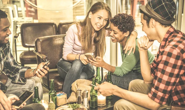 맥주를 마시는 칵테일 바 레스토랑-함께 시간을 즐기는 사람들과 우정 개념-따뜻한 복고풍 필터를 금발 소녀에 초점에서 휴대 전화로 재미 multiracial 친구 — 스톡 사진