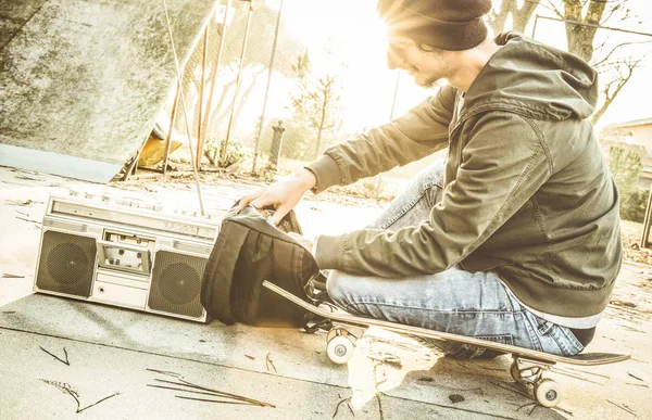 Genç kaykaycı paten kurulu park - gençlik kentsel kavramı olan günbatımında kaykay alternatif adamla - Retro kontrast filtresi güneş halo sunflare ile stereo oyuncu sırt çantası müzik oynamak — Stok fotoğraf