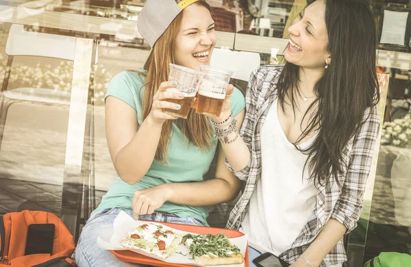 Jovens mulheres comendo pizza e bebendo cerveja no bar restaurante ao ar livre - Conceito de amizade com namoradas felizes se divertindo momentos juntos - Bonitas amigas no filtro vintage dessaturado retro — Fotografia de Stock