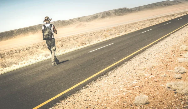 नामीबियन आफ्रिकन वाळवंटात रस्त्यावर चालत माणूस पर्यायी जीवनशैली संकल्पना आणि अज्ञात माणूस बॅकपॅकिंगसह विस्तीर्ण अनुभव जगभरातील प्रवास ट्रिप साहसी रेट्रो फिल्टर — स्टॉक फोटो, इमेज